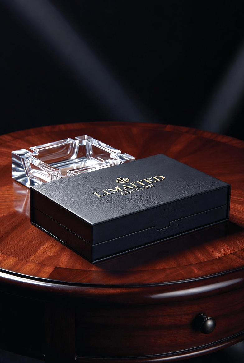 A sleek, limited edition cigarette box on a dark mahogany table, representing the premium cigarette cost.