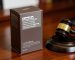 A drab dark brown cigarette pack with health warnings next to a legal gavel, representing plain packaging tobacco laws in Australia.