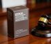 A drab dark brown cigarette pack with health warnings next to a legal gavel, representing plain packaging tobacco laws in Australia.